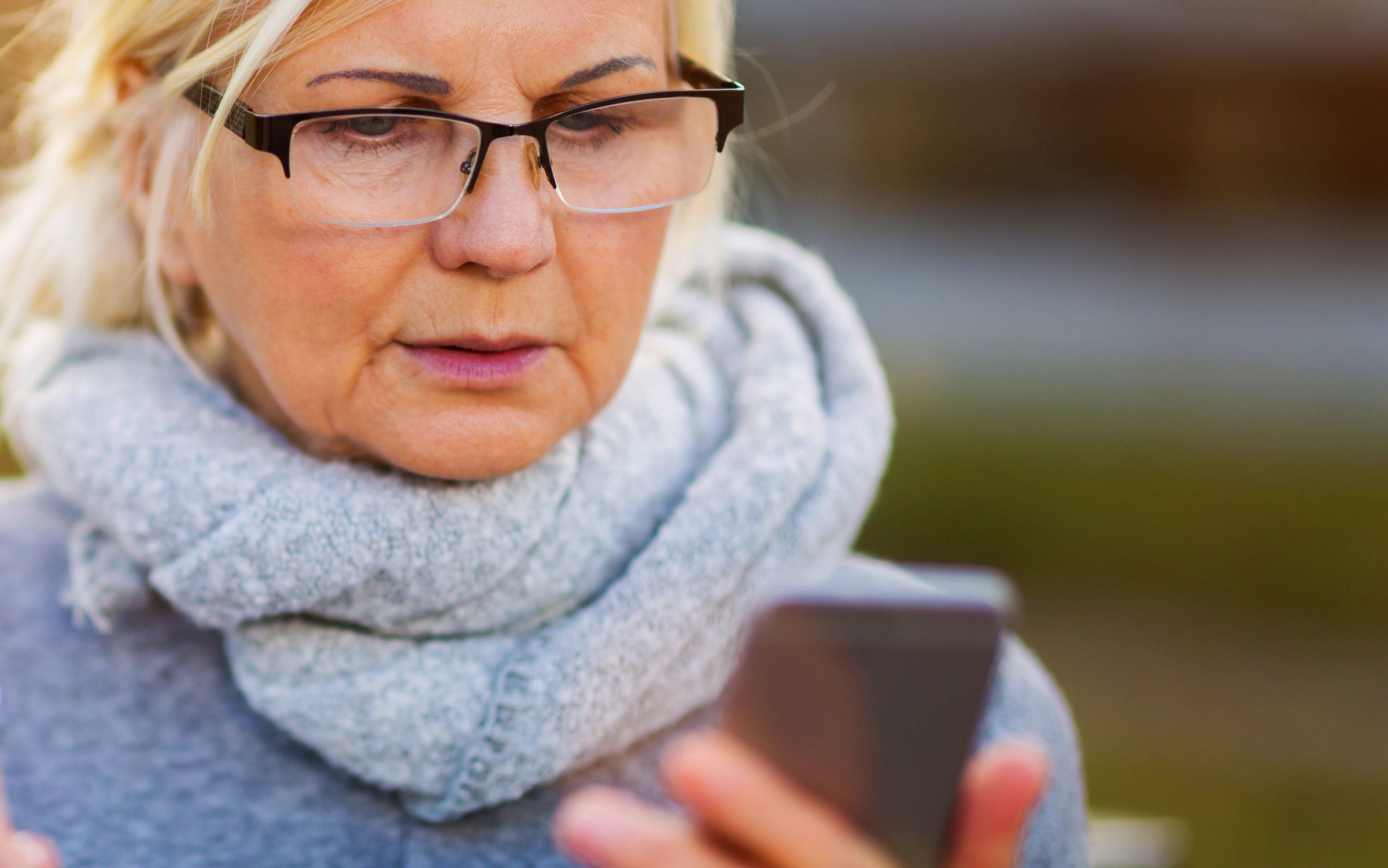 Older woman looking at her smartphone with a worried look